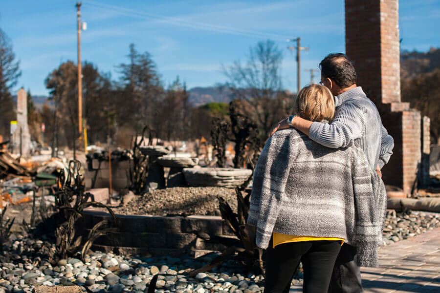 a couple staring at the remains of their burned house