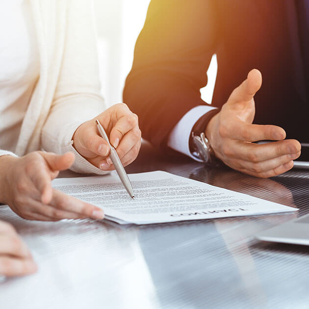 Close-up of hands reviewing and signing a document.