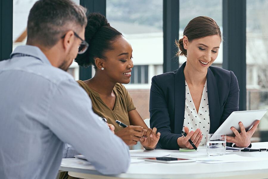 Three people looking at a tablet on a table.