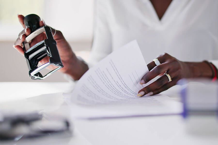 A notary reviewing a document while holding a stamp.