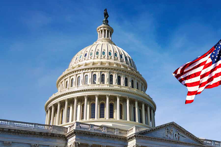 U.S. Capitol dome with an American flag waving on the right side.