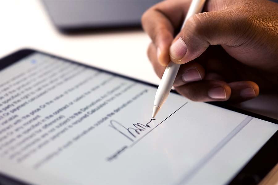 Right male hand using a stylus to sign his signature on a tablet