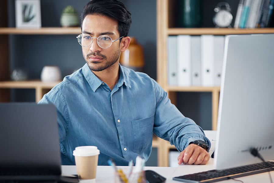 Male Notary in glasses sitting at desk in front of two computer screens