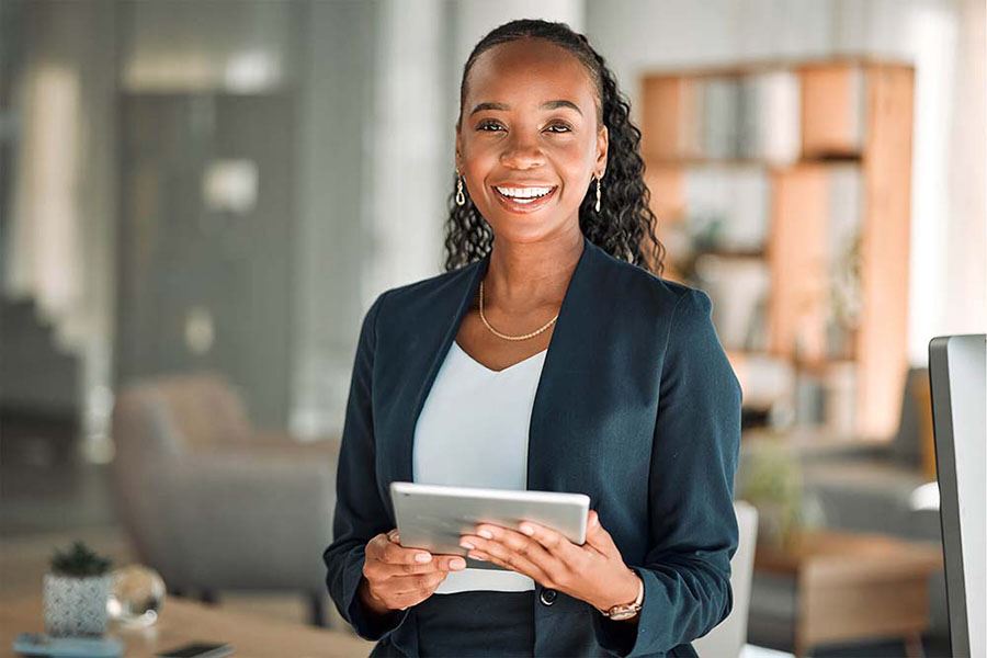 A woman smiles while holding a tablet.