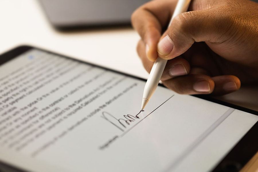 Right hand using a stylus to sign his signature on a tablet