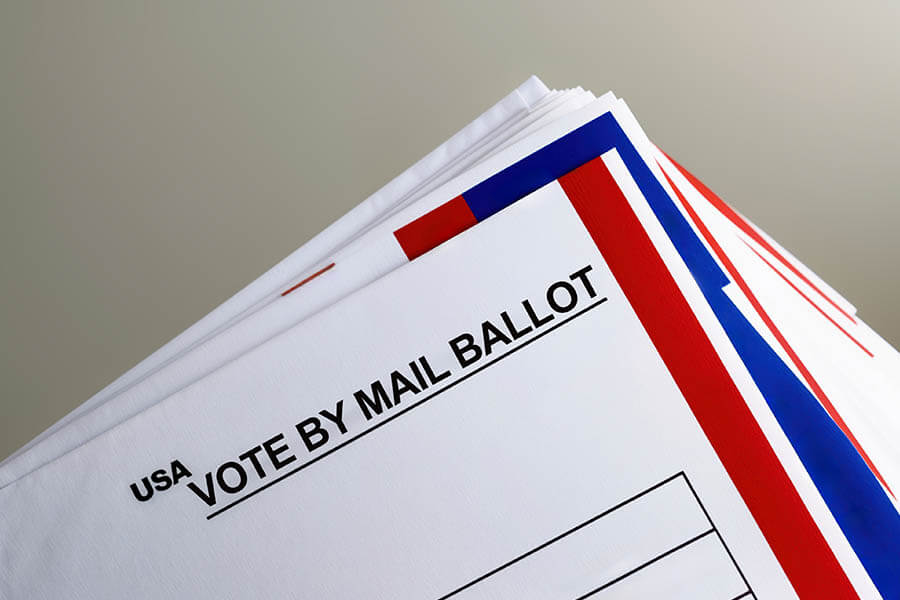 Stack of vote-by-mail ballots on table