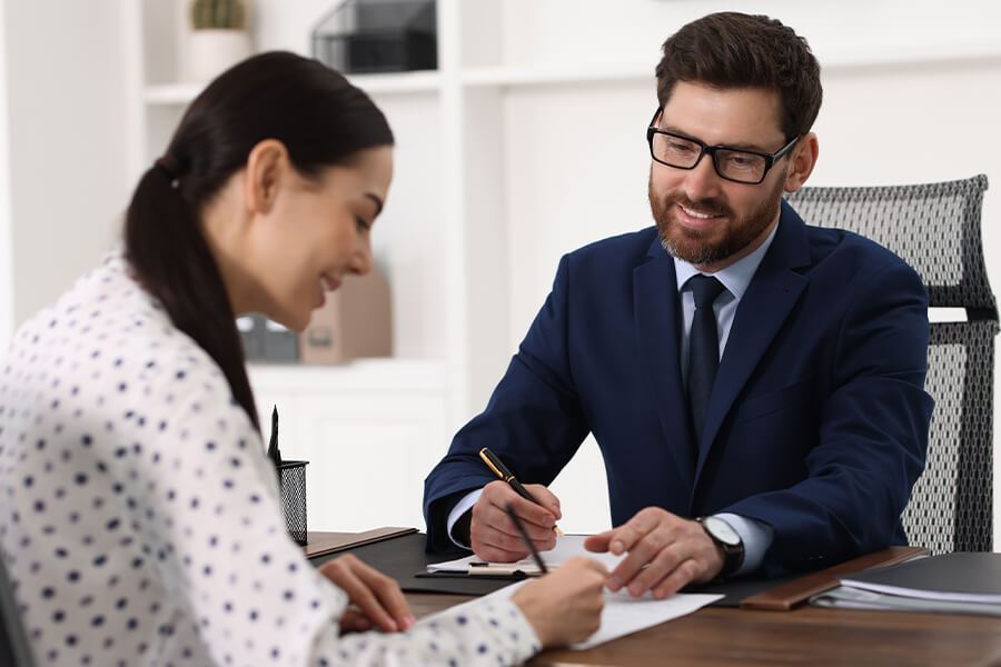 A male Notary and a client in office reviewing and signing documents.