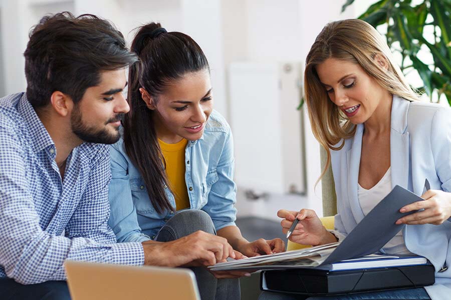 Three people in a business meeting, two women and one man, looking at documents together.