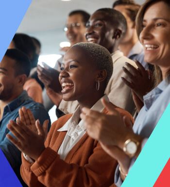 Smiling group of diverse people clapping and cheering at a conference.