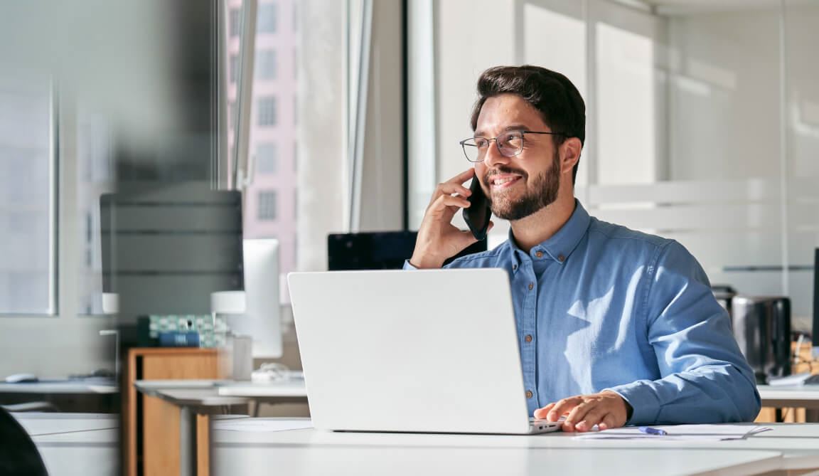 A male Notary speaking on the phone while sitting in front of a laptop